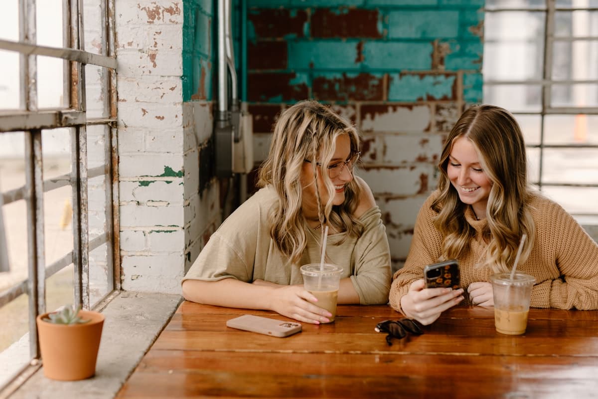 Two guests at a cafe table ordering from a phone
